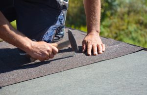 Picture of a roofer installing asphalt shingles.