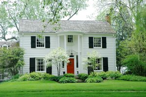 House with white siding, black shutters, and red door